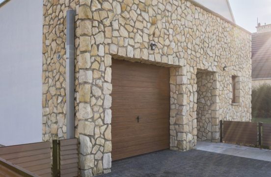 Big house with stone wall and garage in the backyard